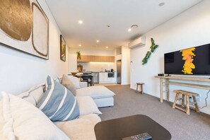 A modern living room with a sofa, a coffee table, and a television. - Christchurch CBD - 2BR with Parking & Balcony (Christchurch)