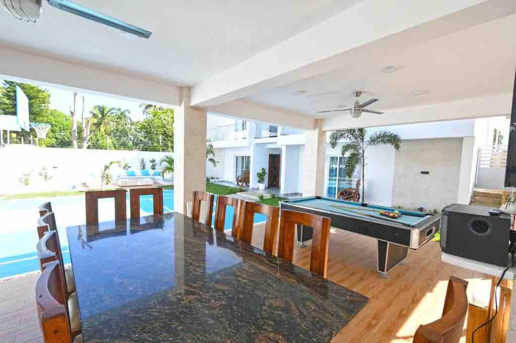 Un espace aménagé au bord de la piscine, comprenant une table de billard, des chaises et une table à manger.