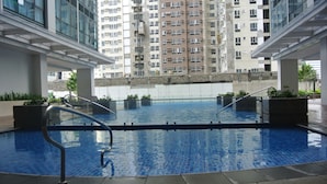 Piscina interna com águas azuis cristalinas, rodeada por arquitetura moderna e vista para edifícios altos.