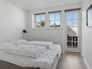 Quarto com cama, escrivaninha e janela com vista para o exterior.