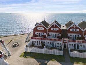 A coastal property with a two-story main building, a white picket fence, and a paved driveway.
