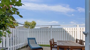 An outdoor patio with a table and chairs, a lounge chair, and a white fence. - "Loan" - 10m to the fjord by Interhome (Nykøbing Sj)