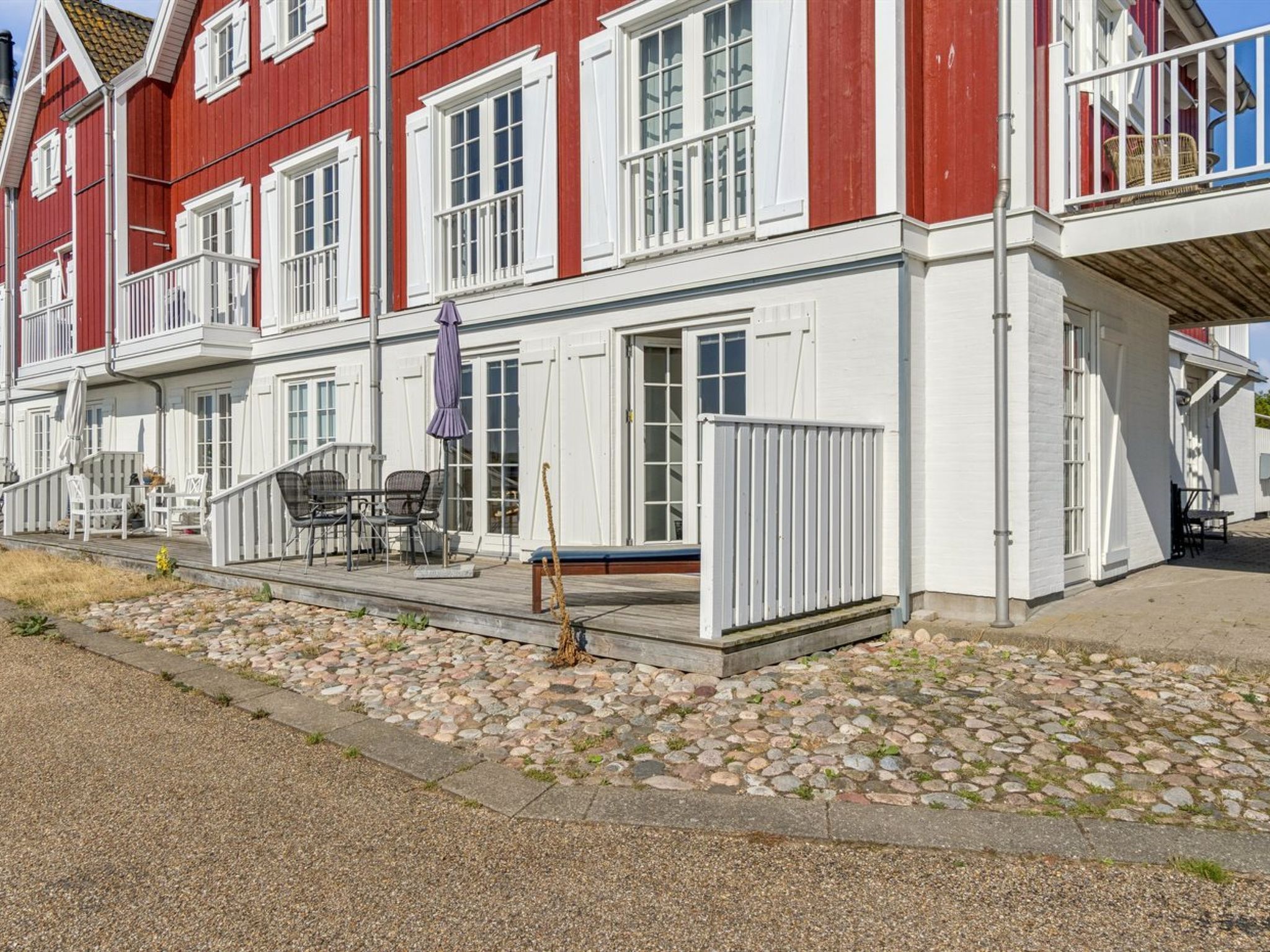 A red and white building with a covered outdoor seating area and a stone-paved entrance.