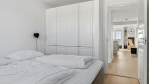 A bedroom with a bed, white wardrobe, and a hallway leading to a living area. - "Loan" - 10m to the fjord by Interhome (Nykøbing Sj)