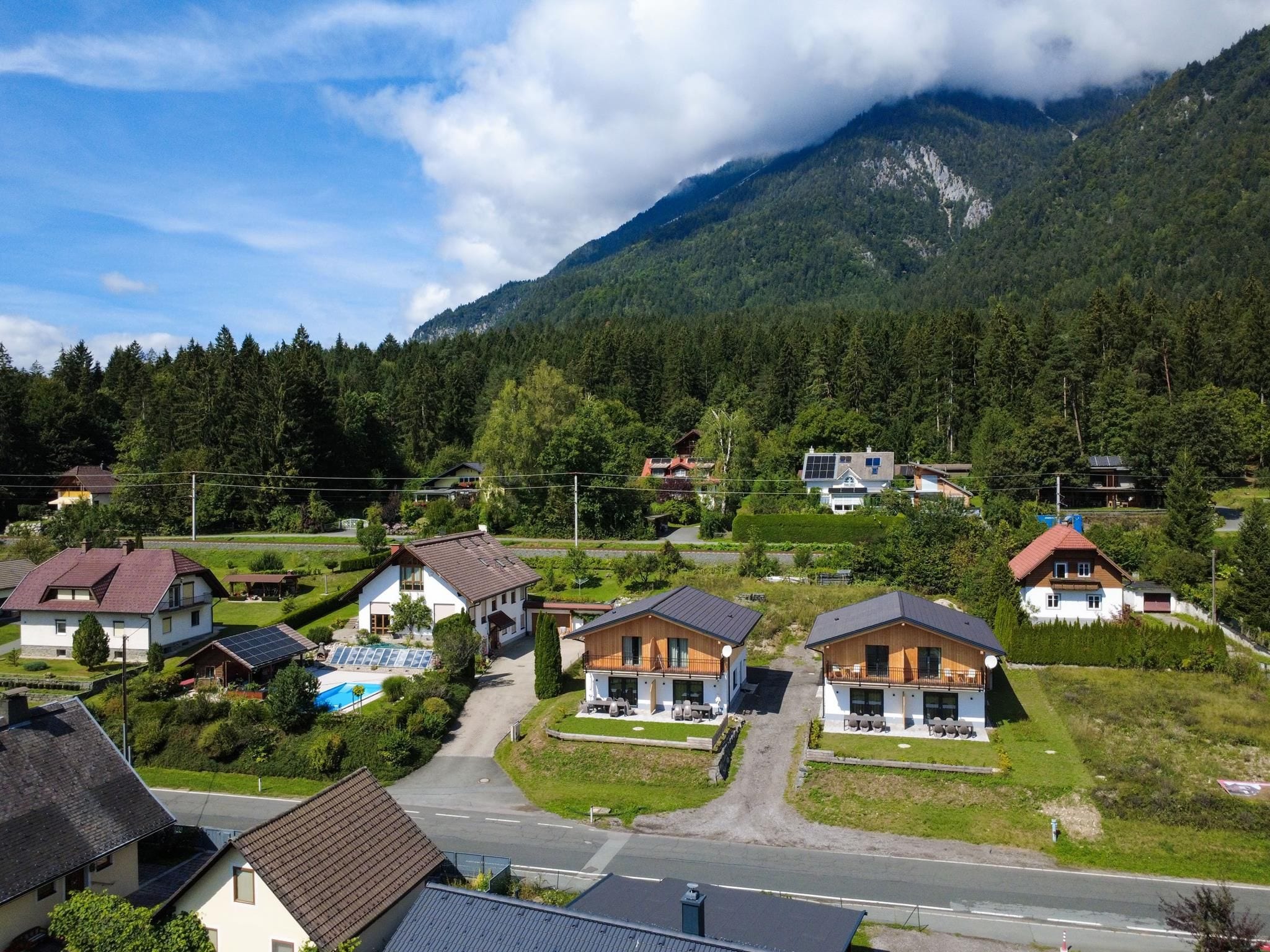 A residential area with houses, a swimming pool, and a mountain backdrop.