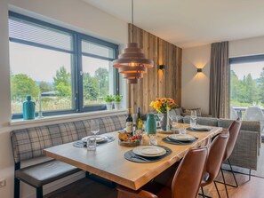 Un comedor moderno con una mesa de madera, asientos tipo banco y vistas al exterior.