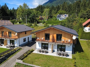Un chalet moderne doté d’un balcon, d’un patio et offrant une vue sur la forêt et les montagnes environnantes.