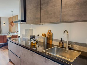 Une cuisine moderne équipée d’un évier en acier inoxydable, d’une machine à café et d’une planche à découper en bois.