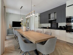 Eine moderne Küche mit einem Holzespeisetisch, grauen Stühlen und Edelstahlgeräten.