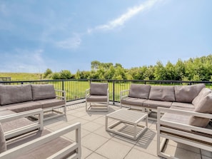 Une terrasse extérieure aménagée avec un ensemble de canapés, un fauteuil et une table basse.