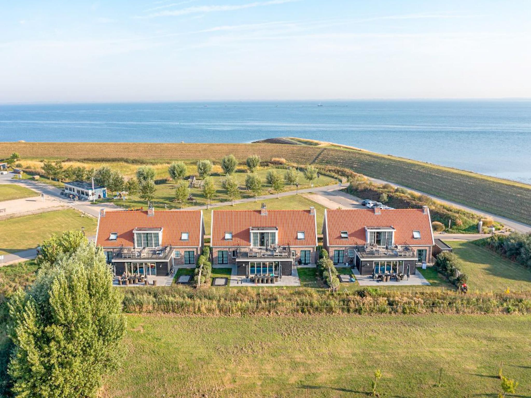 Ein modernes, zweistöckiges Haus mit rotem Ziegeldach, einem Schwimmbad und Blick auf den Ozean.