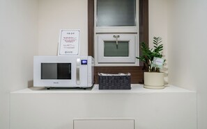 A microwave oven on a white countertop with a small basket and a potted plant beside it. - Incheon Bupyeong Chosunjang (Incheon)