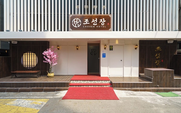 A hotel entrance with a red carpet, a wooden bench, and a potted plant. - Incheon Bupyeong Chosunjang (Incheon)