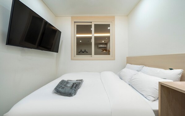 A bedroom with a bed, a TV mounted on the wall, and a window with a view of a room with a hanging light fixture. - Incheon Bupyeong Chosunjang (Incheon)