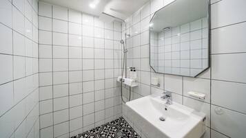 Un baño con azulejos blancos, un lavabo blanco, un espejo y una ducha.