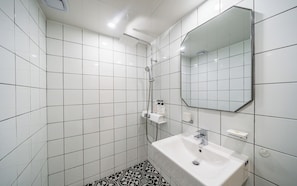 A bathroom with white tiles, a white sink, a mirror, and a shower. - Incheon Bupyeong Chosunjang (Incheon)