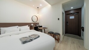 A hotel room with a bed, bedside table, lamp, and a door leading to another room. - Incheon Bupyeong Chosunjang (Incheon)