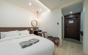 A hotel room with a bed, bedside table, lamp, and a door leading to another room. - Incheon Bupyeong Chosunjang (Incheon)