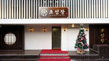 Ein Hotel Eingang mit rotem Teppich, einem Weihnachtsbaum und einem Schild mit der Aufschrift 'CHOSEN HOTEL'.