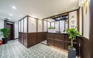 A reception area with a wooden reception desk, a sign with Korean characters, and potted plants.