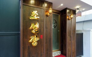 A hotel entrance with wooden paneling, illuminated signage, and a red carpet leading to the door. - Incheon Bupyeong Chosunjang (Incheon)