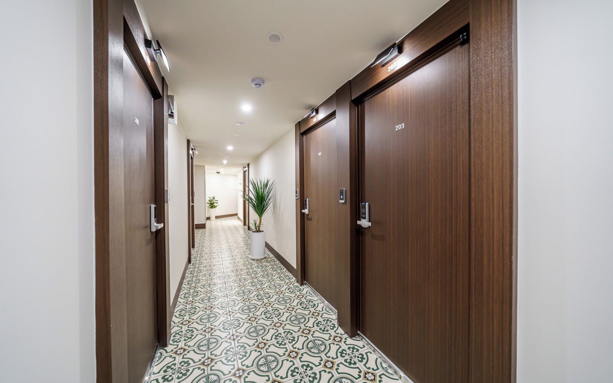 Ein Hotelgang mit Holztüren, deren Nummer 203 ist, und gestalterischen Bodenfliesen.