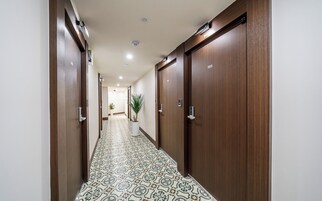 A hotel hallway with wooden doors, numbered 203, and patterned floor tiles.