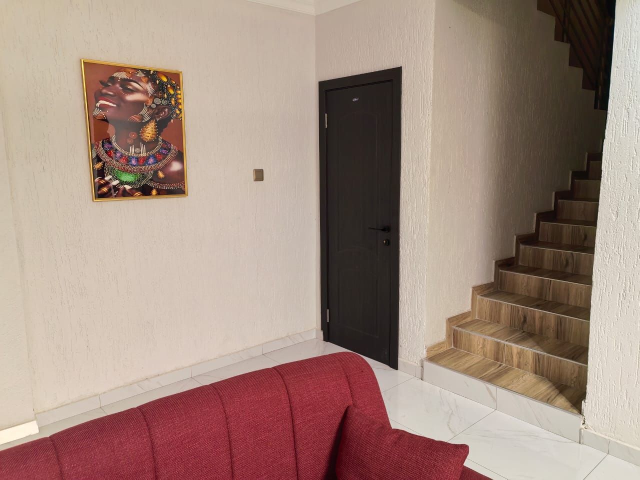 Ein Zimmer mit einem roten Sofa, einer schwarzen Tür und einer Holztreppe.