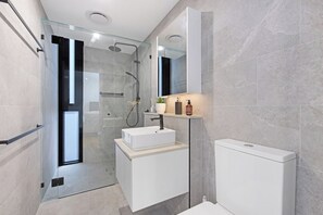 A modern bathroom with a glass-enclosed shower, a white sink, and a toilet. - Oceanview Oasis - Games, Views, Vibes (Southport)