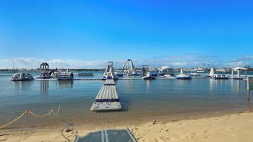 Eine Marina mit vertäuten Booten, ein Sandstrand und ein klarer, blauer Himmel.
