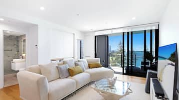 A modern living room with a sofa, a glass coffee table, and a television.