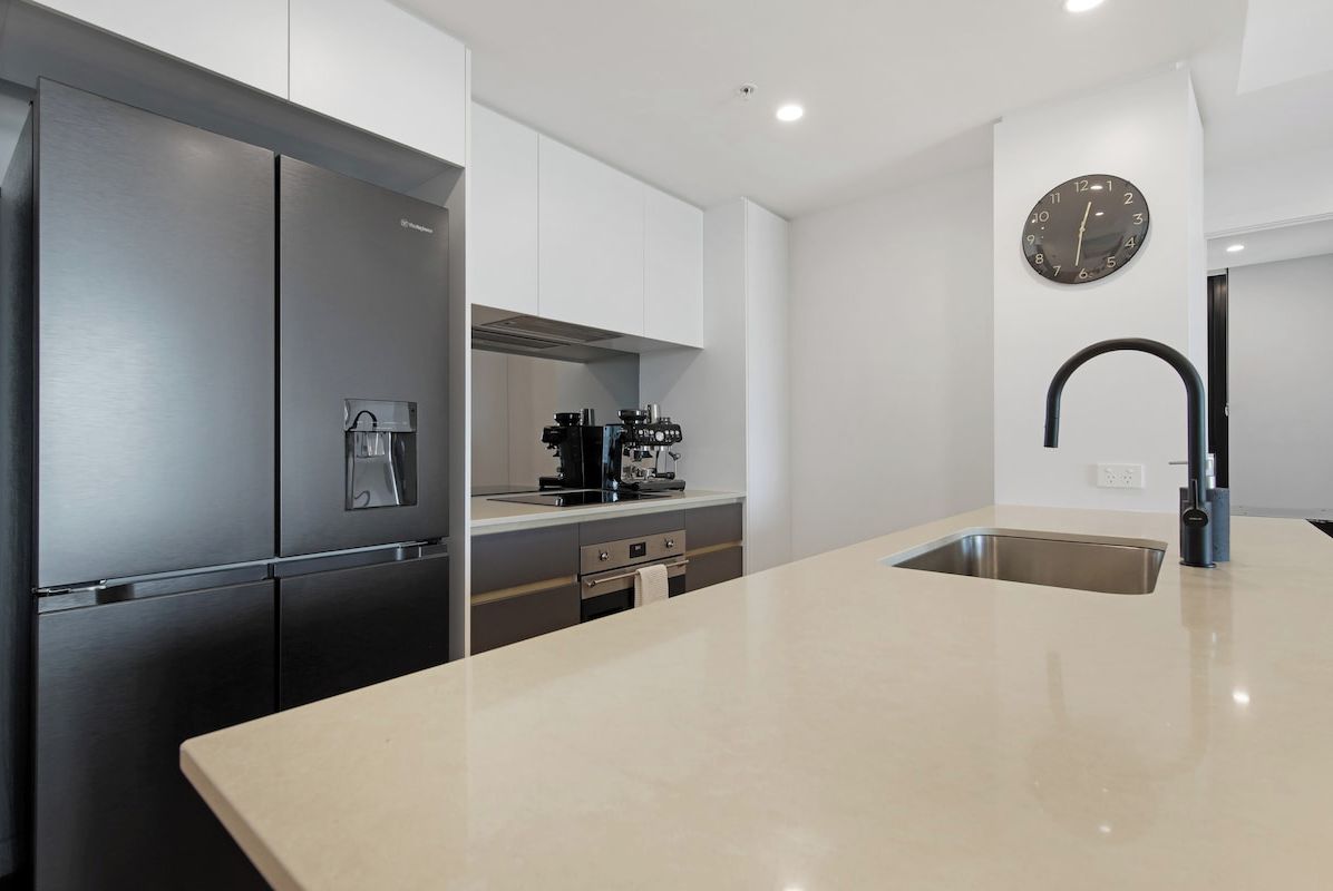 Eine moderne Küche mit einem Edelstahlkühlschrank, einer Kaffeemaschine und einem Spülbecken.