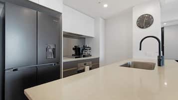 Eine moderne Küche mit einem Edelstahlkühlschrank, einer Kaffeemaschine und einem Spülbecken.