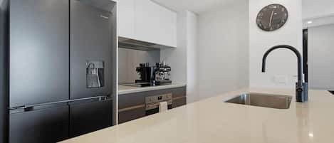 A modern kitchen with a stainless steel refrigerator, a coffee machine, and a sink.