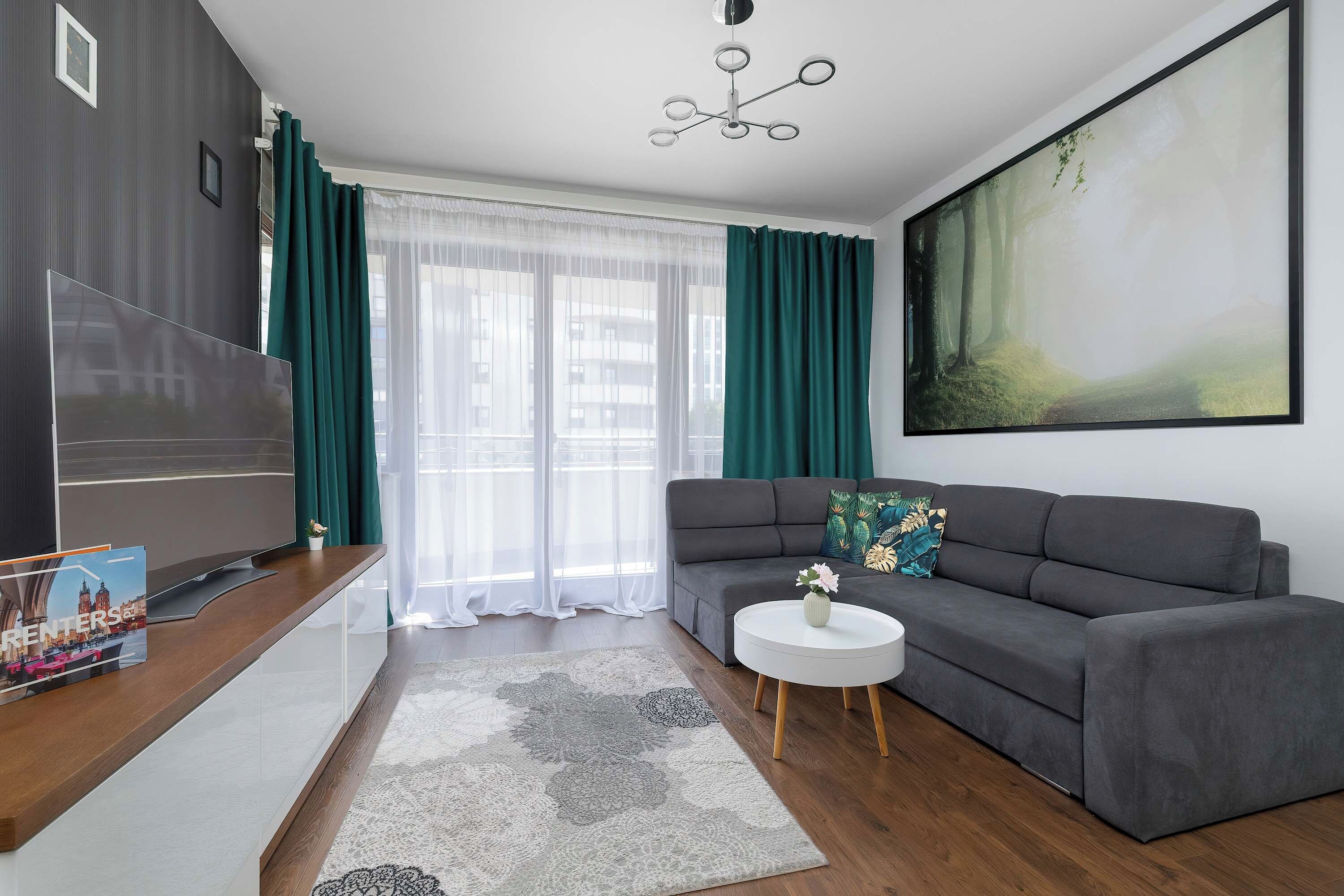 Un salon moderne avec un canapé gris, une table basse blanche et un grand tableau accroché au mur.