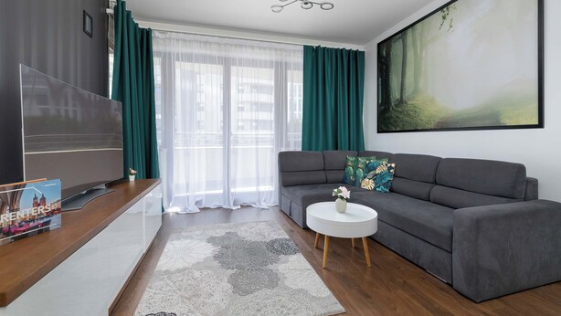 Ein modernes Wohnzimmer mit einem grauen Sofa, einem weißen Couchtisch und einem großen Gemälde an der Wand.