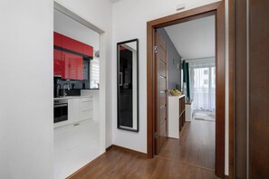 A modern kitchen with white cabinetry, a red accent wall, and a built-in oven.