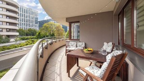 Ein Balkon mit Tisch, Stühlen, einer Obstschale und einer Kanne.