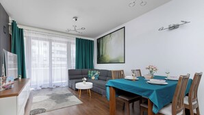 Ein modernes Wohnzimmer mit Essbereich, einer Couch, einem Couchtisch und einem Gemälde an der Wand.