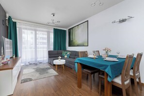 Uma sala de estar moderna com área de jantar, sofá, mesa de centro e um quadro na parede.