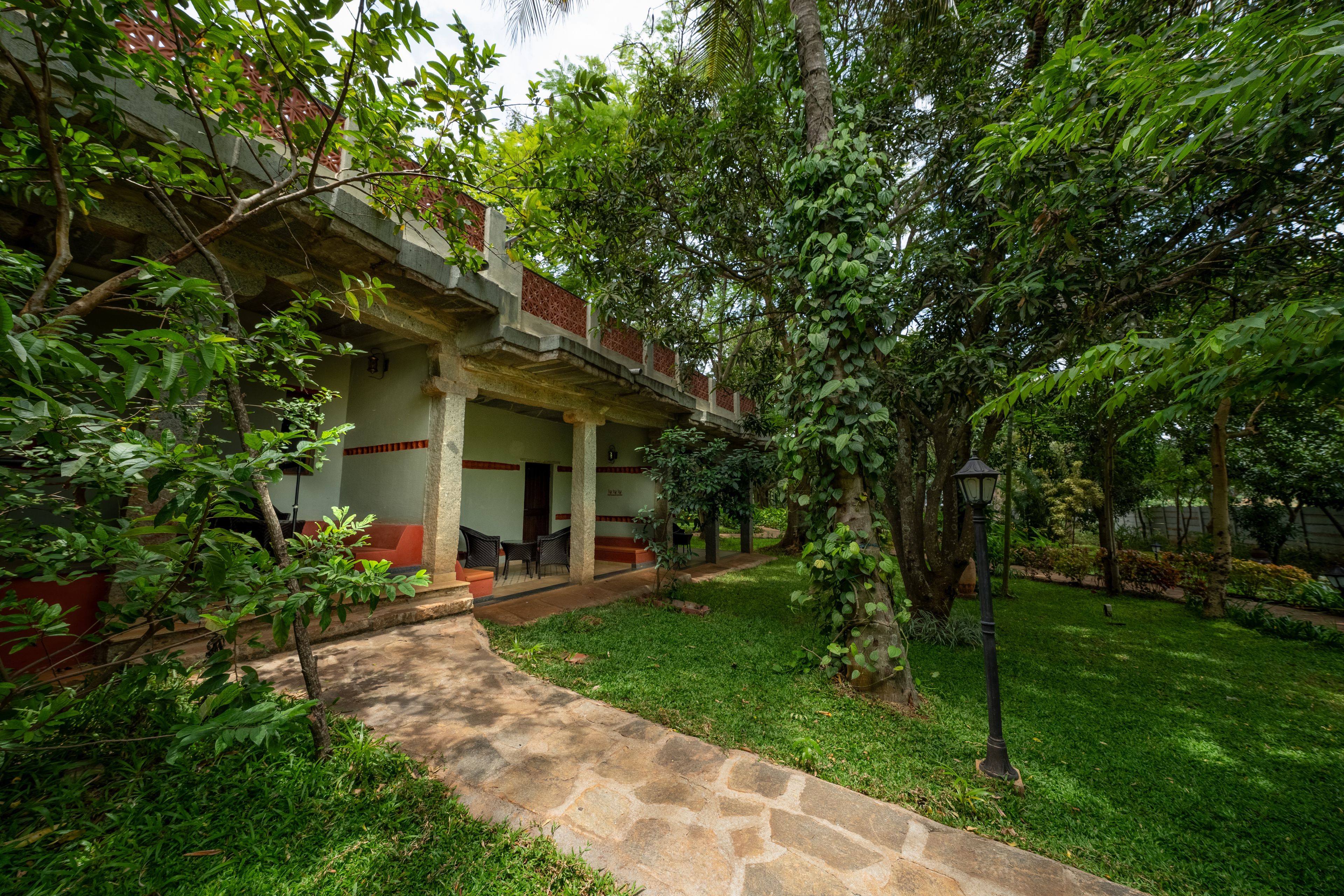 A courtyard with a stone pathway leading to a covered seating area with chairs and a table.