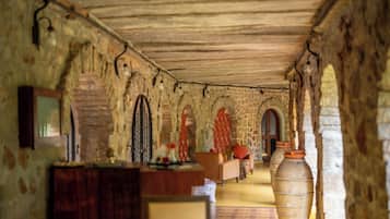 A corridor with stone walls, wooden ceiling, and arched doorways.