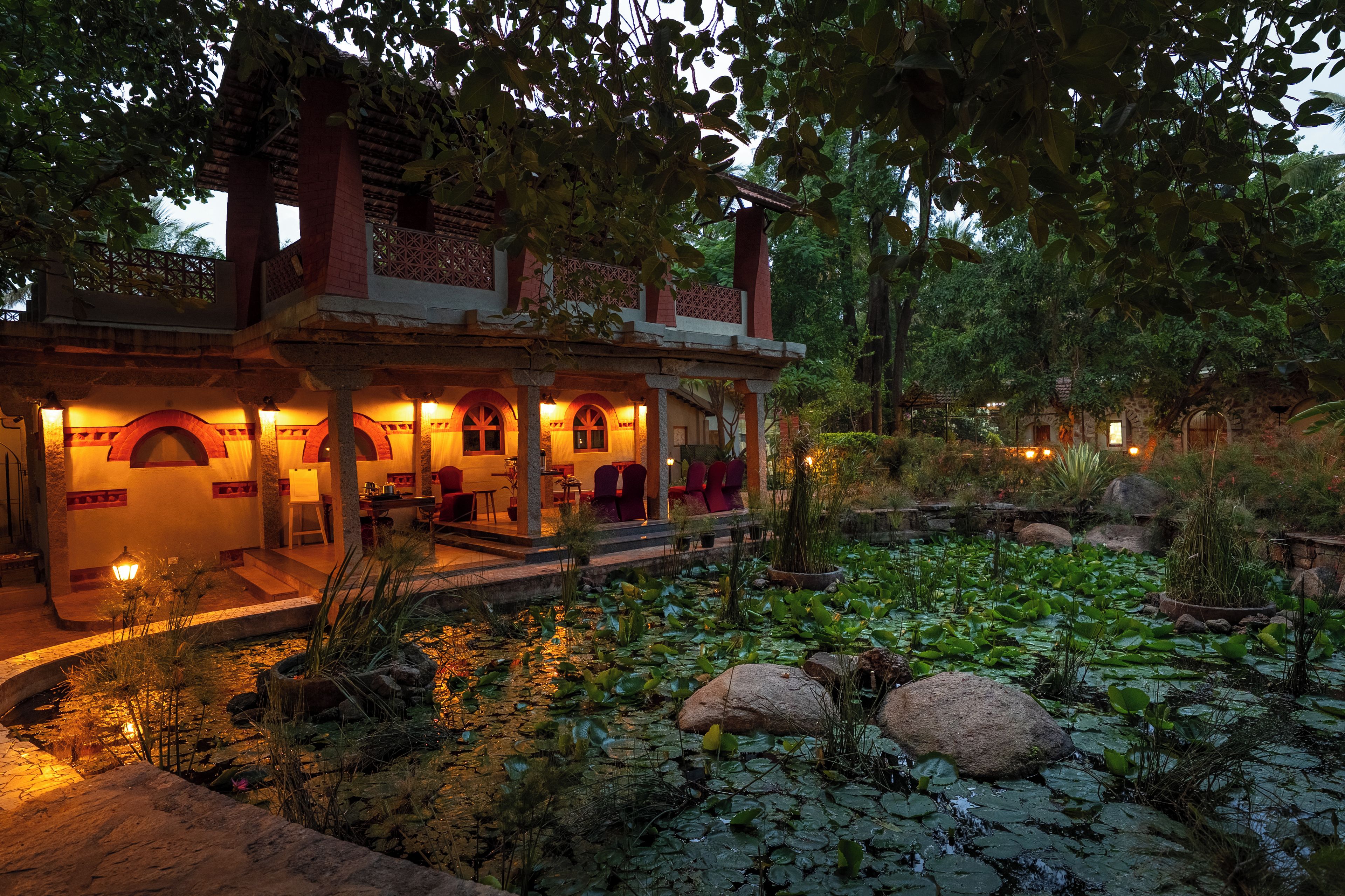 A traditional building with a covered patio and a pond with lily pads.