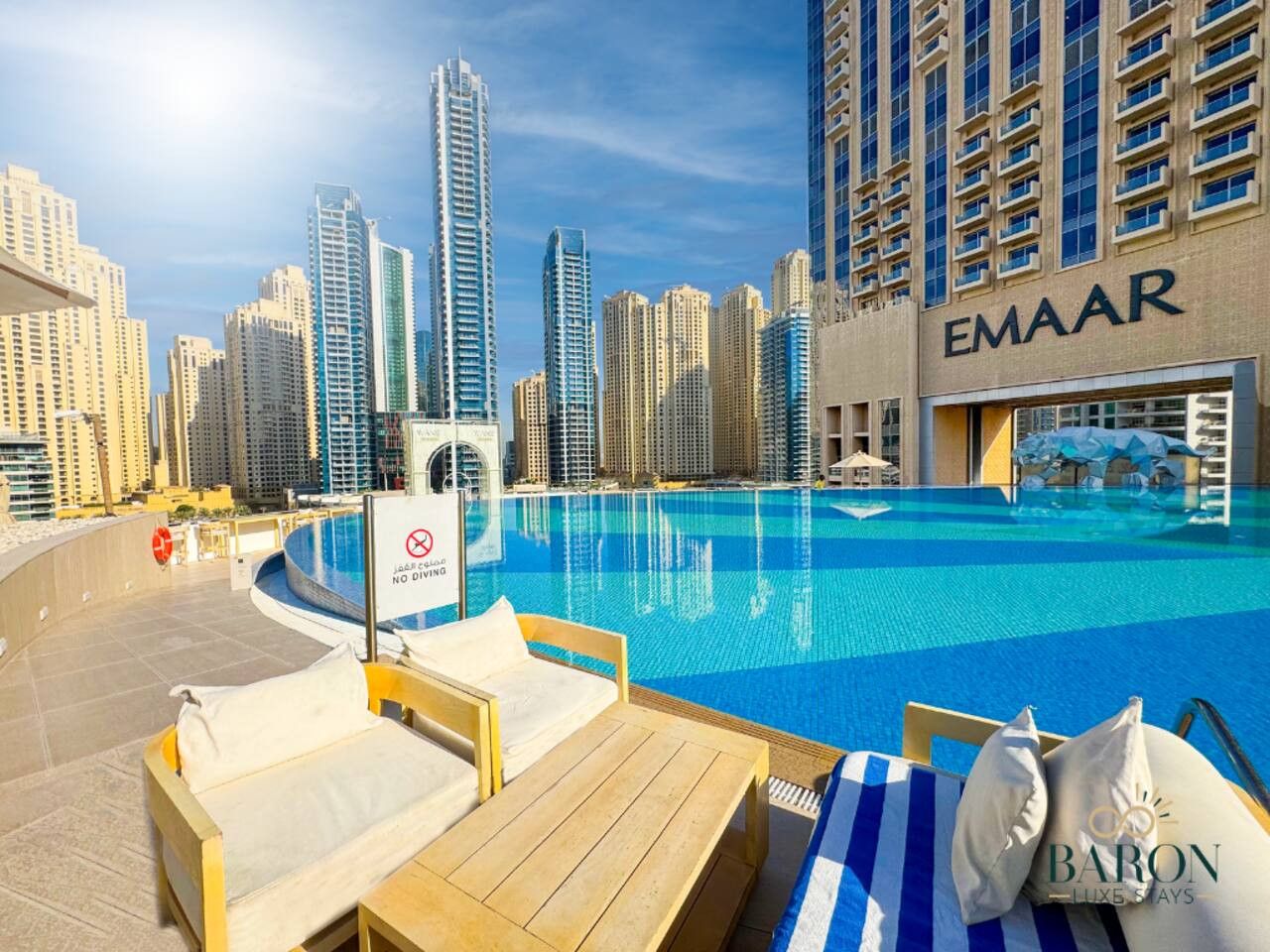 A poolside area with lounge chairs and a sign indicating no diving.