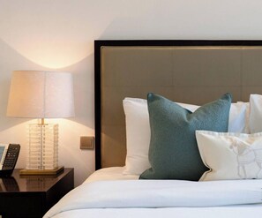 A hotel room with a bed, pillows, a nightstand with a lamp, and a telephone. - The Splendid • JW Marriott (Dubai)