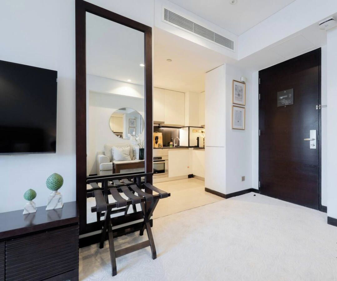 Interior moderno de un apartamento con sala de estar, cocina y una puerta de madera oscura.