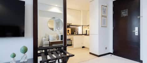 L’intérieur d’un appartement moderne, comprenant un espace de vie, une cuisine et une porte en bois foncé.