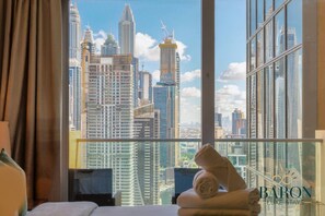 A hotel room with a large window offering a view of a city skyline. - The Splendid • JW Marriott (Dubai)