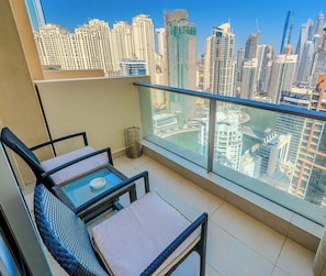 A balcony with two chairs and a small table, overlooking a cityscape with high-rise buildings. - The Signature • JW Marriott (Dubai)