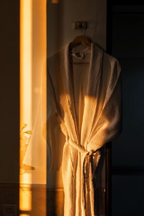 Una bata colgada de un perchero de madera en una habitación con una puerta y un accesorio de iluminación en la pared.